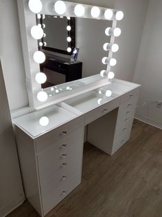 a white vanity with lighted mirror and drawers