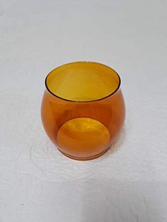 an orange glass bowl sitting on top of a white table