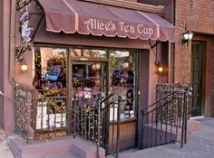 the entrance to an alice's tea cup shop with pink walls and wrought iron railings