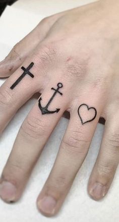 a person with two tattoos on their fingers, one has an anchor and the other has a heart