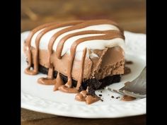 a piece of cake with chocolate and white icing on a plate next to a knife