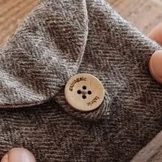 a person holding a button on top of a piece of cloth