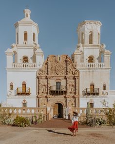 a woman standing in front of a large building with two towers on it's sides