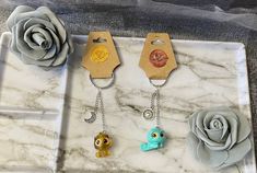 three key chains with flowers on them sitting on a marble tray