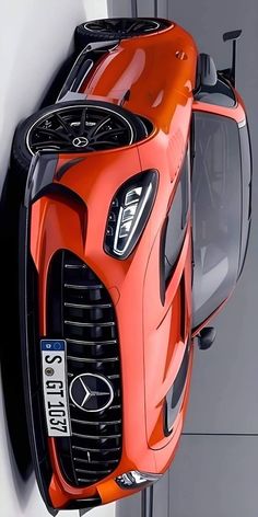 an orange sports car hanging from the side of a white wall next to a door