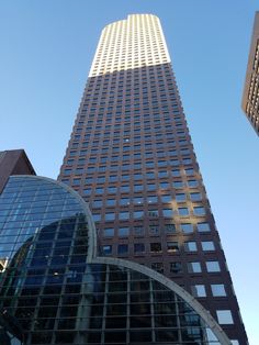 the tall building has many windows on it's sides and is next to other buildings