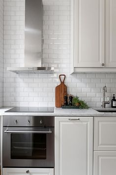 a kitchen with white cabinets and stainless steel stove top oven, dishwasher and cutting board on the counter