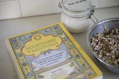 a book sitting on top of a table next to a bowl of cereal and a jar of milk