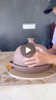 a woman is making a vase out of clay with her hands on the top of it