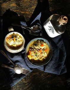 two bowls of soup are sitting on a table next to spoons and a salt shaker