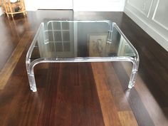 a clear glass coffee table sitting on top of a wooden floor