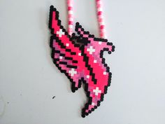 a pink and black beaded necklace on a white surface with beads hanging from it