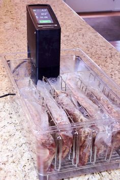 some meat in plastic containers sitting on top of a counter next to an appliance