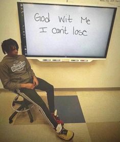 a man sitting on a chair in front of a large screen with writing on it