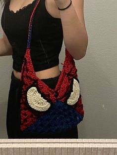 a woman taking a selfie with her cell phone in front of her face and wearing a crocheted bag