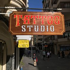 a sign that says tattoo studio hanging from the side of a building on a city street