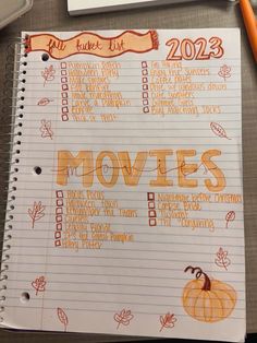 a notebook with the words movies written on it next to a cup of coffee and an orange marker