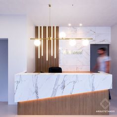 an office lobby with marble counter top and gold lighting fixture hanging from the ceiling above it