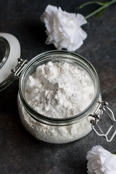 a glass jar filled with white powder next to a flower