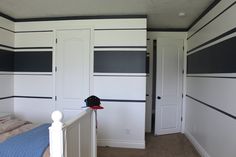 a bedroom with black and white stripes painted on the walls, closets in the corner