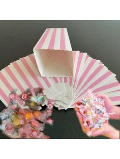 pink and white striped paper fan with candy in it's hand next to other items