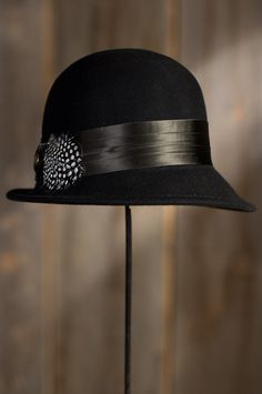 Rising to fashion in the 1920s under the French word for bell, the cloche is the feminine hat of choice for sophistication and simplicity that can be tilted to the side. The Vilma Cloche embraces the mood and spirit of 1950s jazz, with a 4 ½”crown, an asymmetrical 1½”– 2 ½” brim, and a wide 2” band detailed with a spotted pheasant feather bow on pleated silk. Crafted from premium wool felt from New Zealand, the Vilma crowns you with vintage beauty. 100% wool with satin lining. Imported. Classic Adjustable Costume Hats And Headpieces For Winter, Vintage Fedora For Fall Party, Chic Fitted Cloche Hat With Flat Brim, Winter Retro Adjustable Fedora, Gatsby Style Adjustable Hat With Curved Brim, Gatsby Style Wide Brim Adjustable Hats, Adjustable Curved Brim Gatsby Hat, Adjustable Fur Felt Hat For Kentucky Derby, Chic Adjustable Brimmed Top Hat