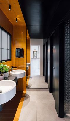 a bathroom with two sinks, mirrors and plants on the counter top next to each other