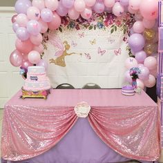 a table with pink and purple balloons on it