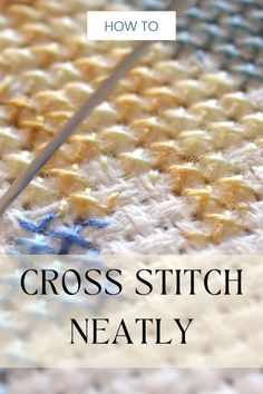 the cross stitch needle is being used to work on a piece of fabric with text overlay