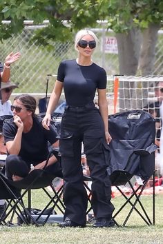 a woman in black outfit standing next to a soccer ball