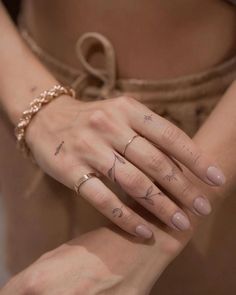 a woman's hand with tattoos on her left wrist and two fingers in the middle