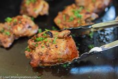 some meat is being cooked in a skillet with tongs and garnishes