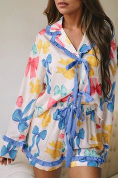 Embrace your inner elegance with our Bow Print Tied Ruffled Pajama Set, a delightful blend of comfort and Southern Belle charm. Perfect for cozy spring mornings or relaxing at home, this pajama set combines playful bow prints with delicate ruffle... Cute Floral Print Sleepwear For Pajama Party, Cute Floral Print Sleepwear For Spring, Spring Ruffled Sleepwear For Loungewear, Feminine Blue Sleepwear For Pajama Party, Spring Ruffled Pajamas For Pajama Party, Cute Ruffled Sleepwear For Spring, Spring Sleepwear With Ruffles, Feminine Blue Sleepwear For Spring, Cute Ruffled Sleepwear For Loungewear