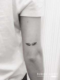 a person with a small wing tattoo on their left arm and the other arm behind them