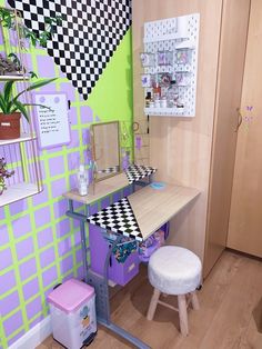 a room with a checkered wall, desk and stool in the corner next to a potted plant