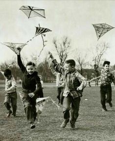 black and white photograph of children running with kites