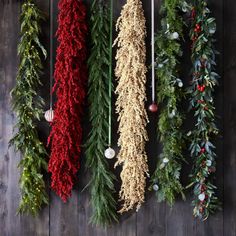 christmas garlands hanging on the wall with ornaments and greenery around them in various colors