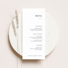 a white plate with a menu on it next to a fork and some dried flowers