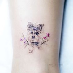 a small dog with flowers on the side of her leg is shown in this tattoo design