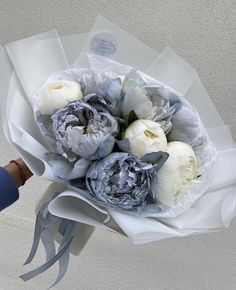 a bouquet of flowers is being held by a person's hand with blue gloves