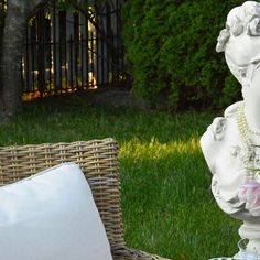 a white statue sitting on top of a grass covered field next to a basket filled with flowers