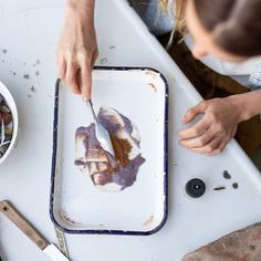 a person is cutting up food on a white table with bowls and utensils