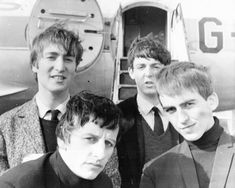 four young men standing next to each other in front of an airplane