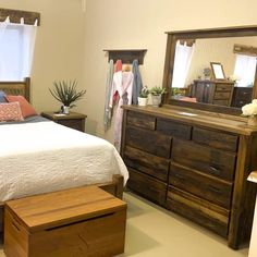 a bed room with a neatly made bed and wooden dresser next to a mirror on the wall