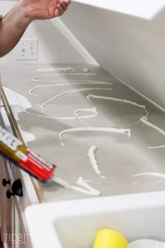 a person is painting on the wall with white paint