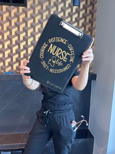 a woman holding up a black book with the words nurse written on it in front of her face