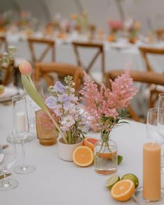 the table is set with flowers, oranges and wine glasses for an elegant wedding reception