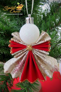 an ornament hanging from a christmas tree decorated with red and gold ribboning