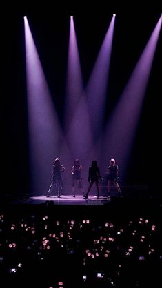 a group of people standing on top of a stage in front of purple light beams