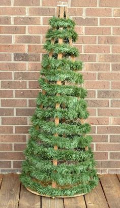 a small green christmas tree sitting on top of a wooden floor next to a brick wall